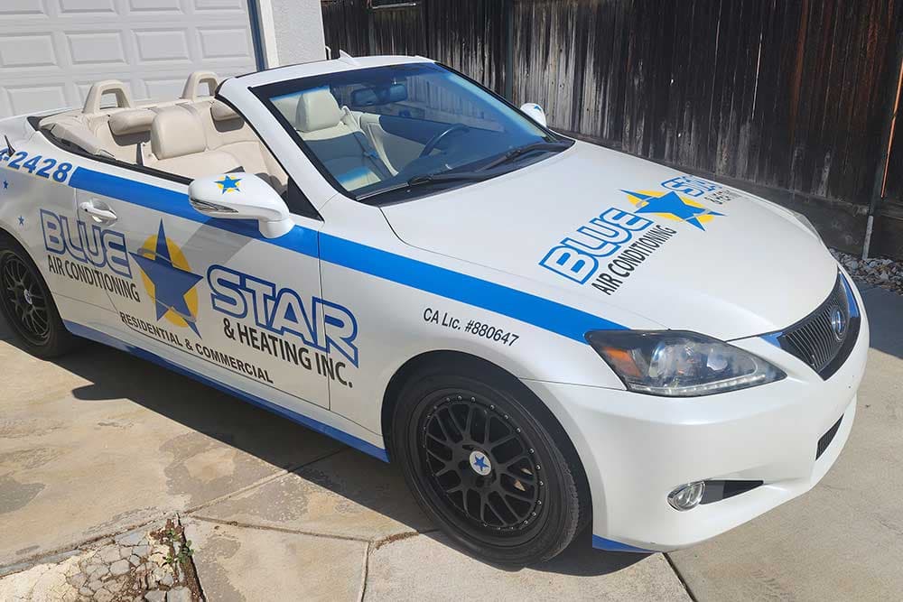 Alexus, a white Lexus convertible wrapped in Blue Star logos and blue stripes, parked in a driveway