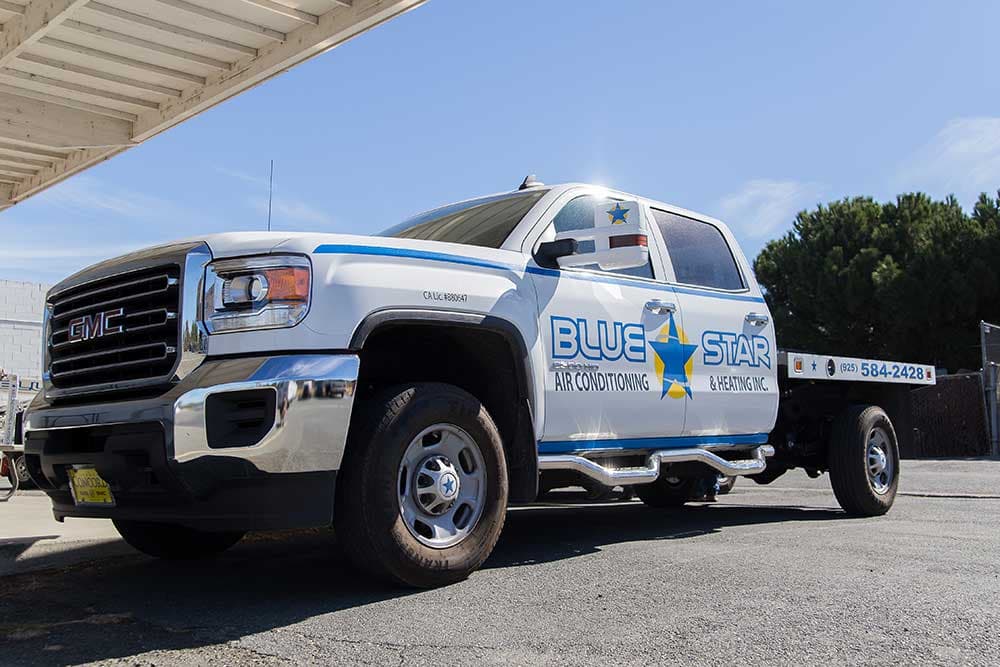 Flatty, a white Blue Star GMC Sierra 2500HD flatbed truck with blue pinstripes and the Blue Star logo