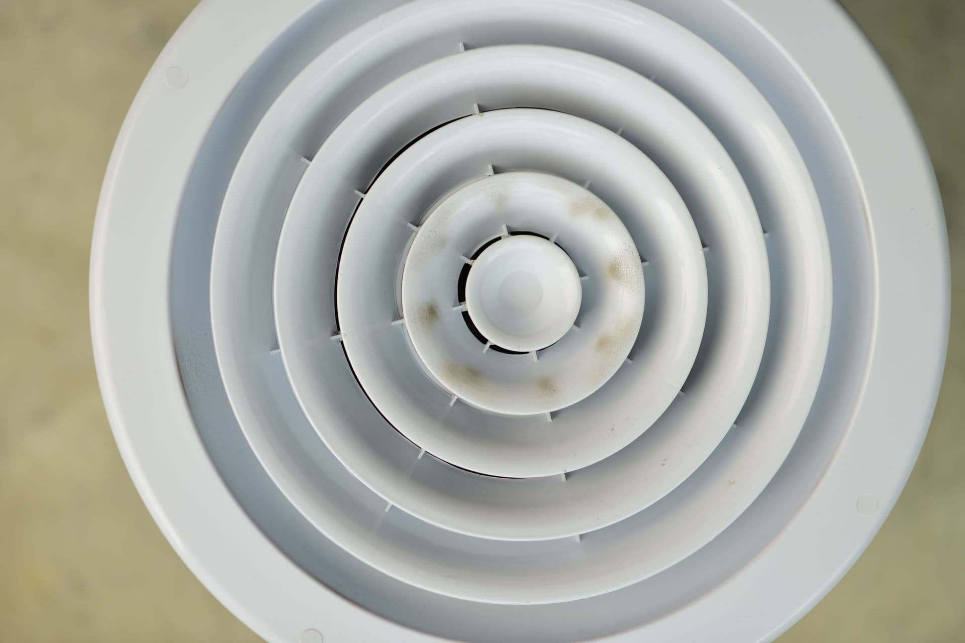 Close-up of a round ceiling air diffuser with dust marks on its concentric rings