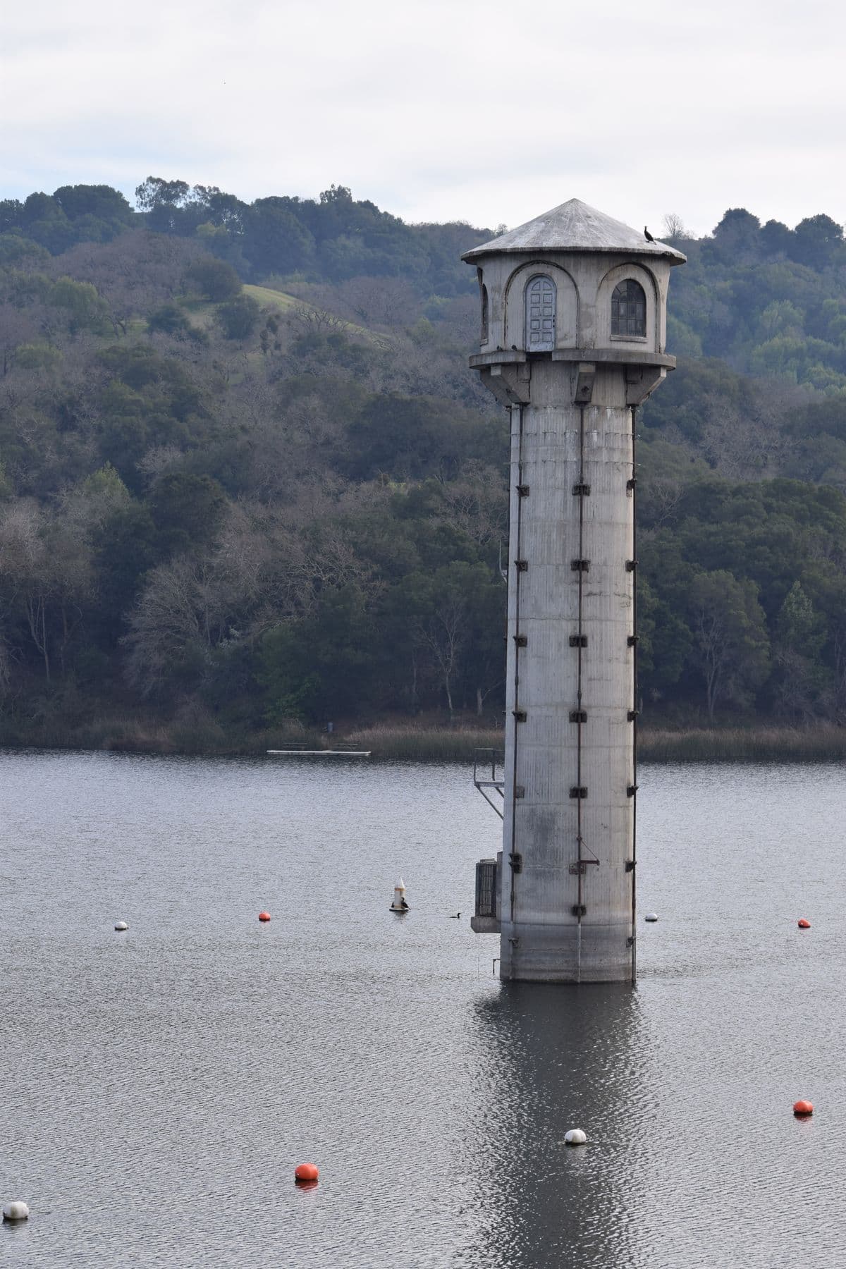 The historic intake tower standing in Lafayette Reservoir beneath oak-covered hills