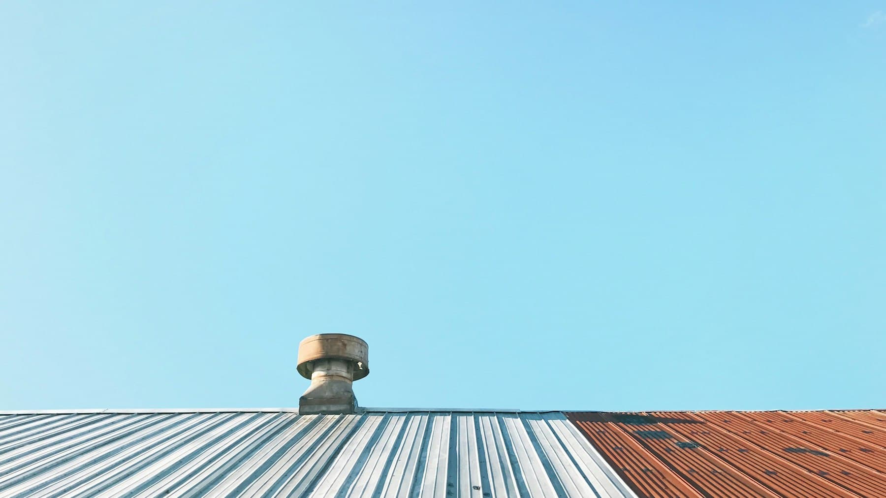 Turbine roof ventilator on a corrugated metal roof against a clear blue sky