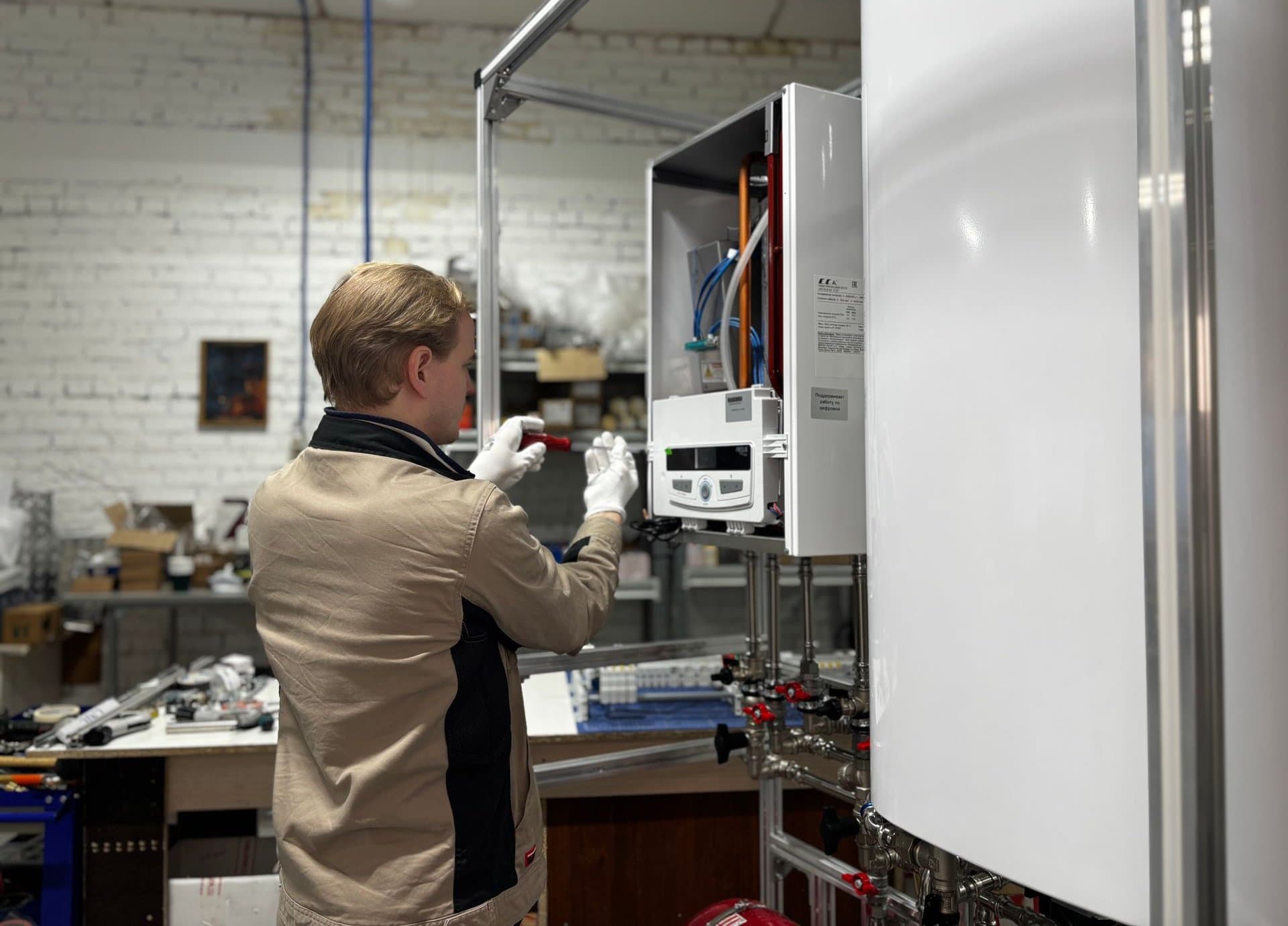 Technician in white gloves adjusting the controls of a wall-mounted gas heating unit in a workshop