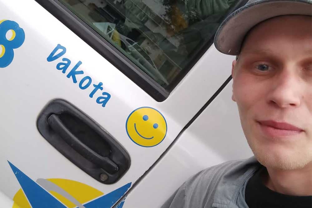 Dakota of Blue Star beside a Blue Star truck door lettered with his name and a smiley face