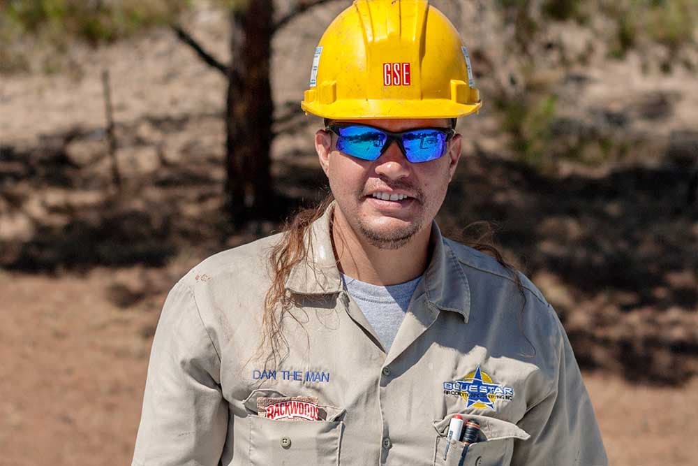 Dan the Man of Blue Star in a yellow hard hat, mirrored sunglasses and a Blue Star work shirt