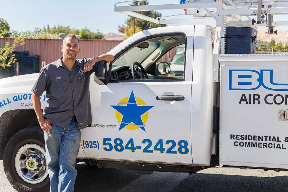 Kevin of Blue Star leaning on the door of a white Blue Star service truck showing the (925) 584-2428 phone number