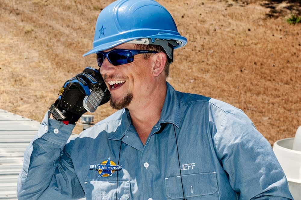 Jeff of Blue Star laughing on the phone in a blue hard hat and a Blue Star work shirt