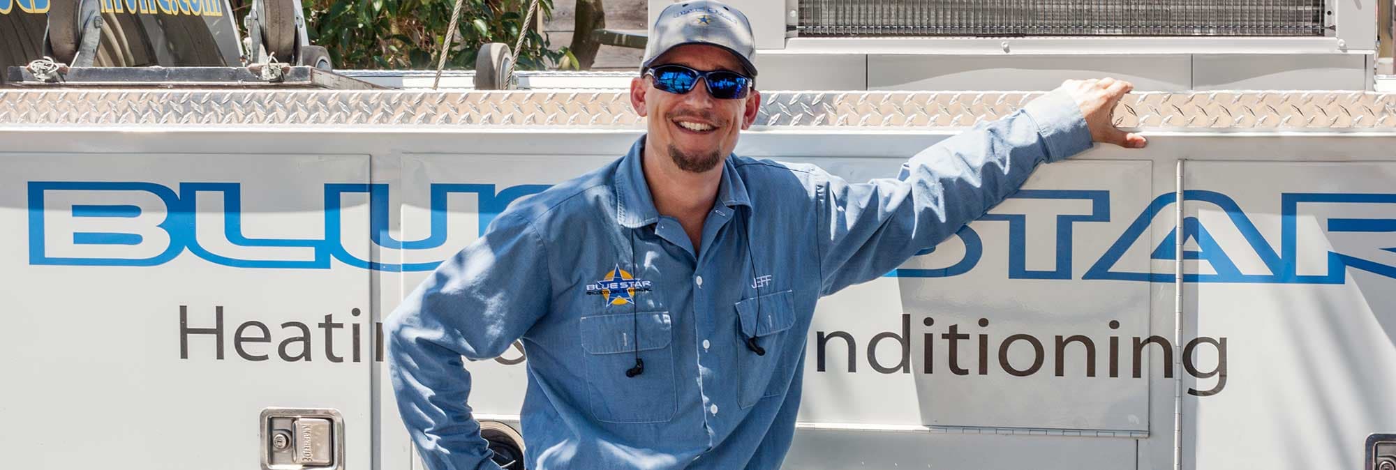 Jeff of Blue Star smiling beside the Blue Star Heating & Air Conditioning lettering on a service truck