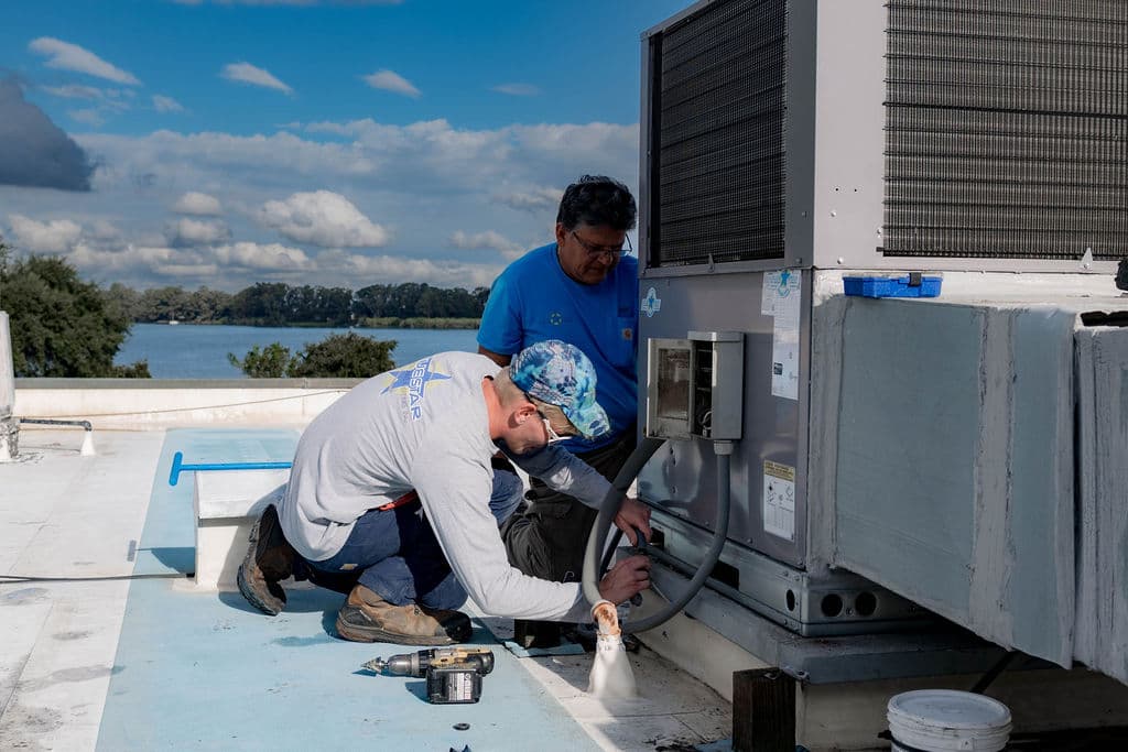 Blue Star technicians running electrical conduit into the side of a new packaged rooftop unit